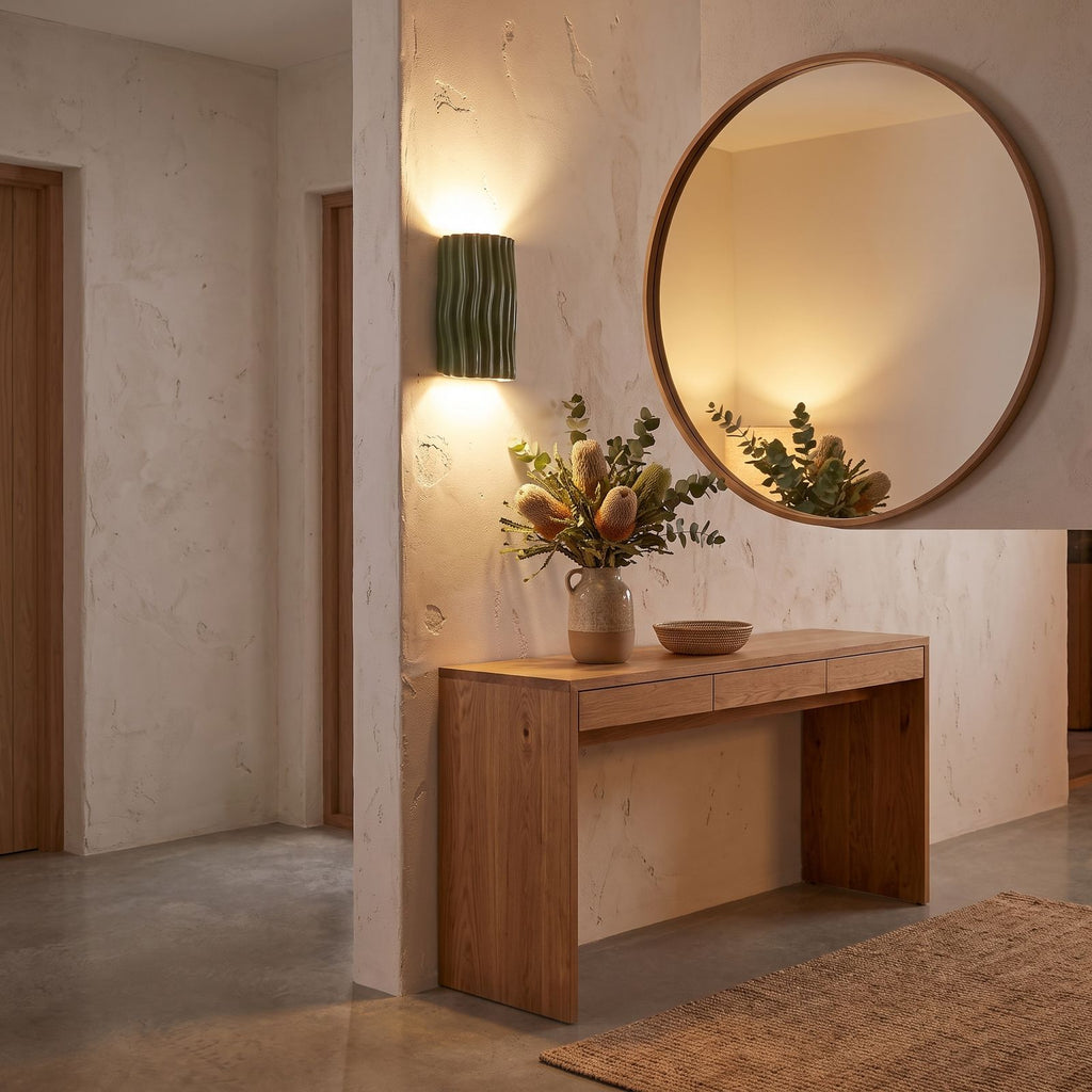Wavy ribbed resin up down wall light beside a round mirror in an entry hall