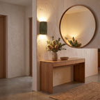 Wavy ribbed resin up down wall light beside a round mirror in an entry hall