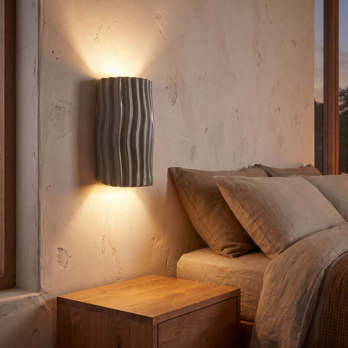Wavy Ribbed Resin Half Cylinder Up Down Wall Light in grey beside a bed