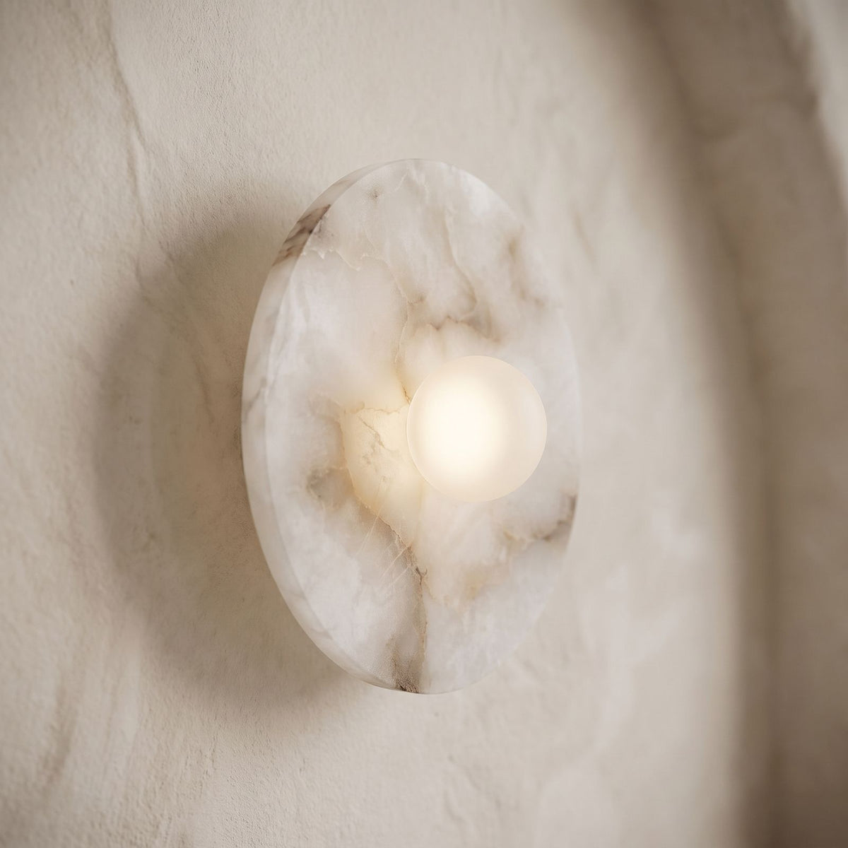 White Alabaster Halo Wall Light, close view at 45 degrees on a plaster wall
