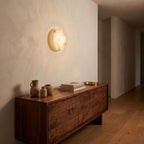 White Alabaster Halo Wall Light in a hallway above a timber console