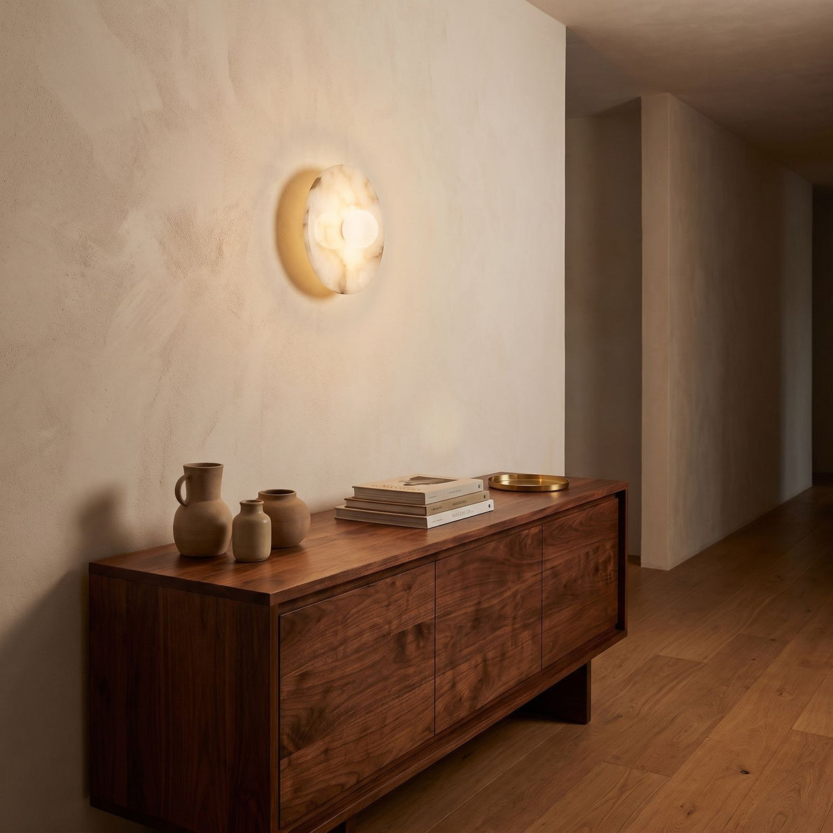 White Alabaster Halo Wall Light in a hallway above a timber console