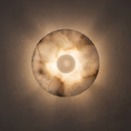 White Alabaster Halo Wall Light glowing on a plaster wall at night