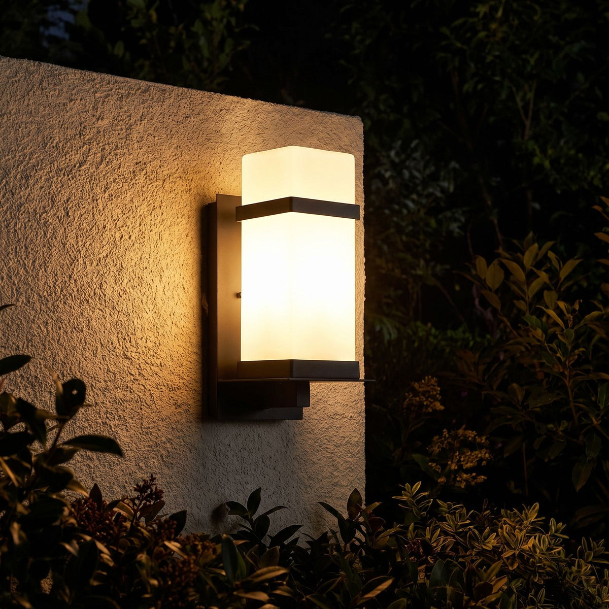 White Glass Black Iron Outdoor Wall Light glowing on a garden wall at night