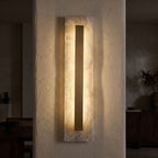 Wide Alabaster Panel Brass Wall Light glowing on a plaster wall at night