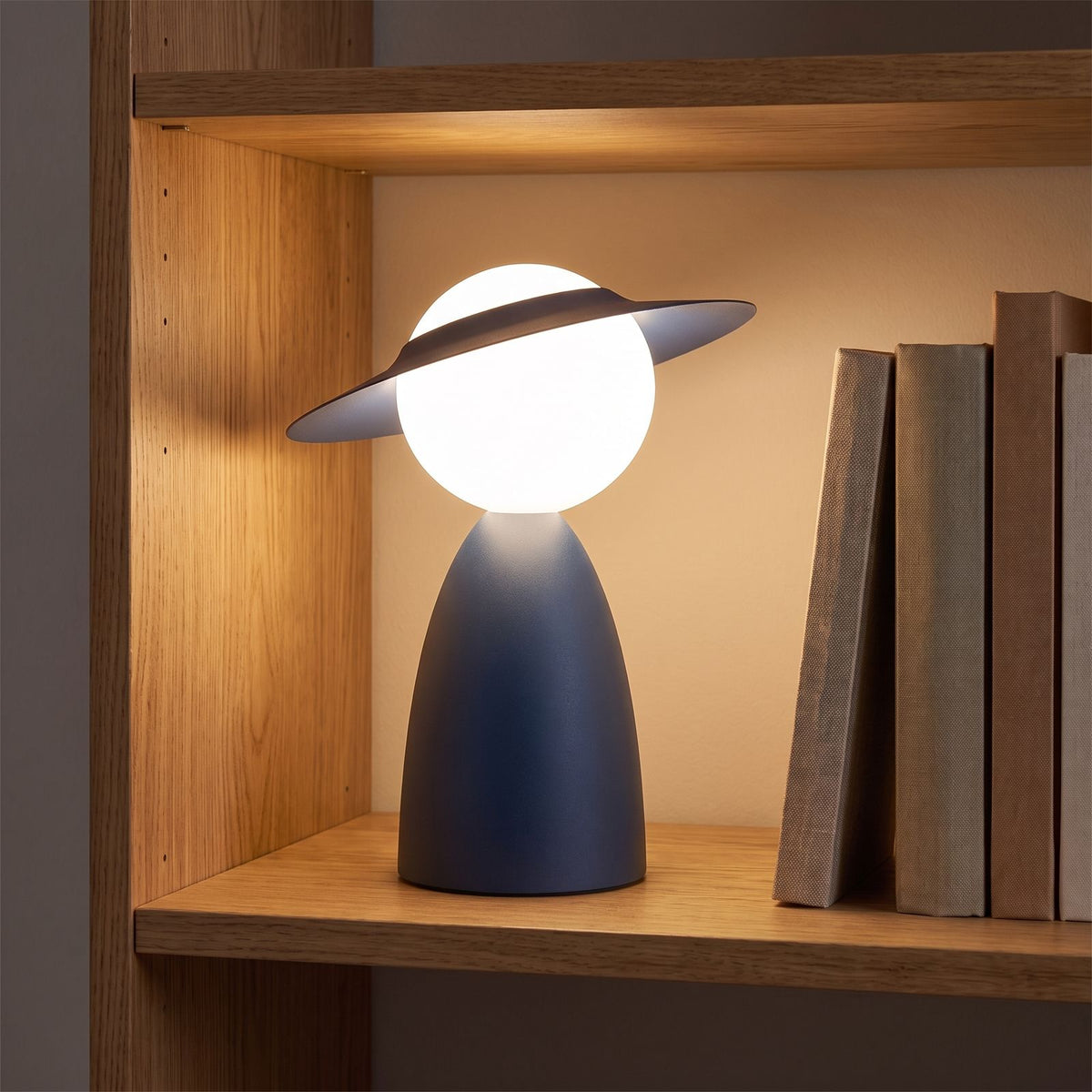 Wide brim hat glass globe table lamp on an oak shelf beside books