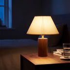 Wood Base Cone Shade Bedside Table Lamp switched on beside a bed at night
