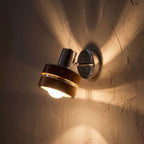 Wood Cylinder Shade Iron Disc Wall Light glowing on a plaster wall at night