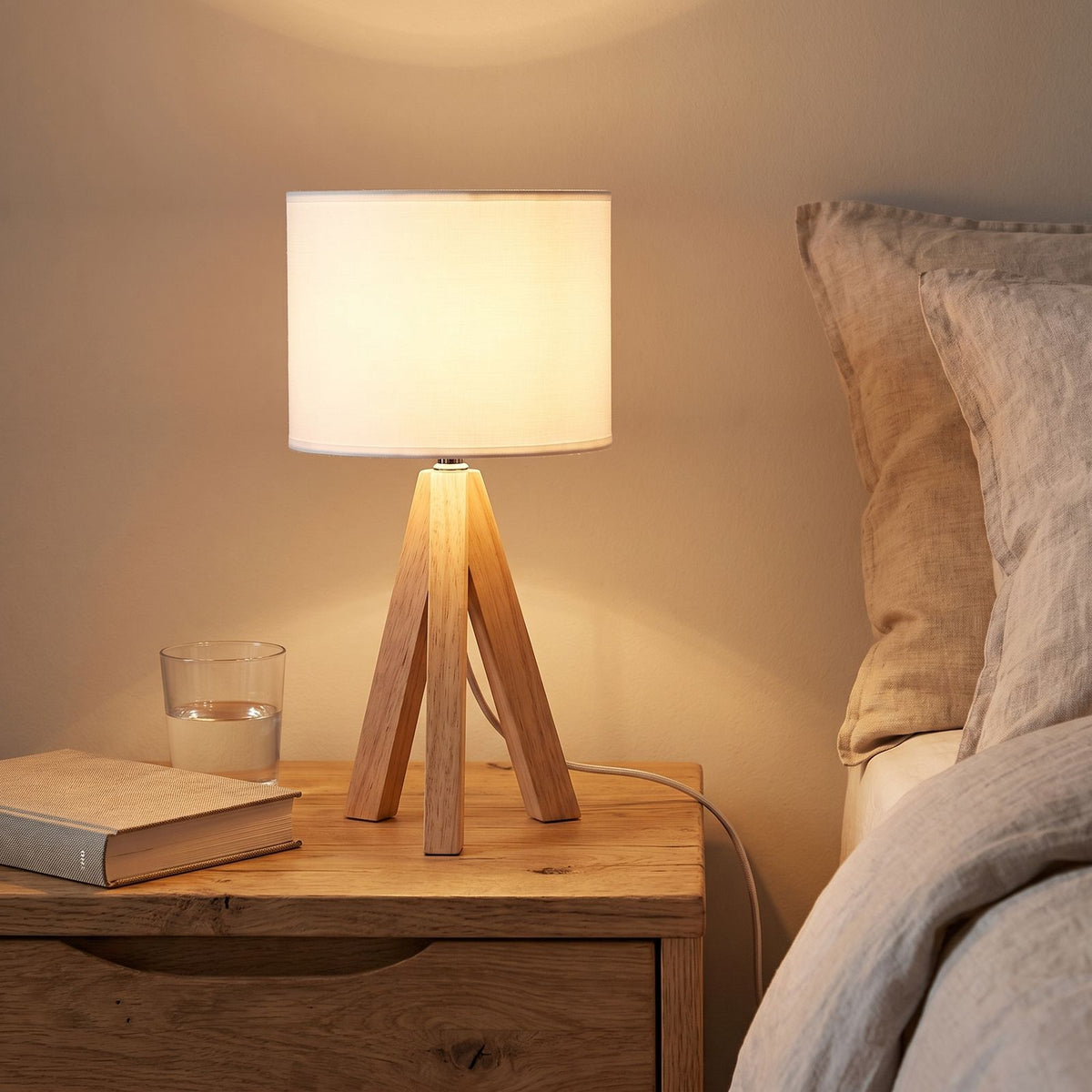 Wood Tripod Drum Shade Bedside Table Lamp on a bedside table