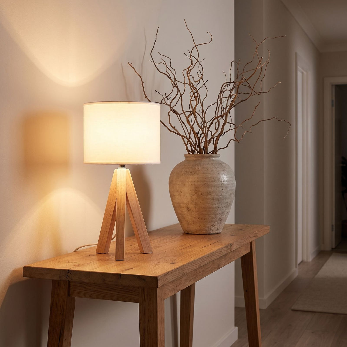 Wood tripod drum shade table lamp on an entry console