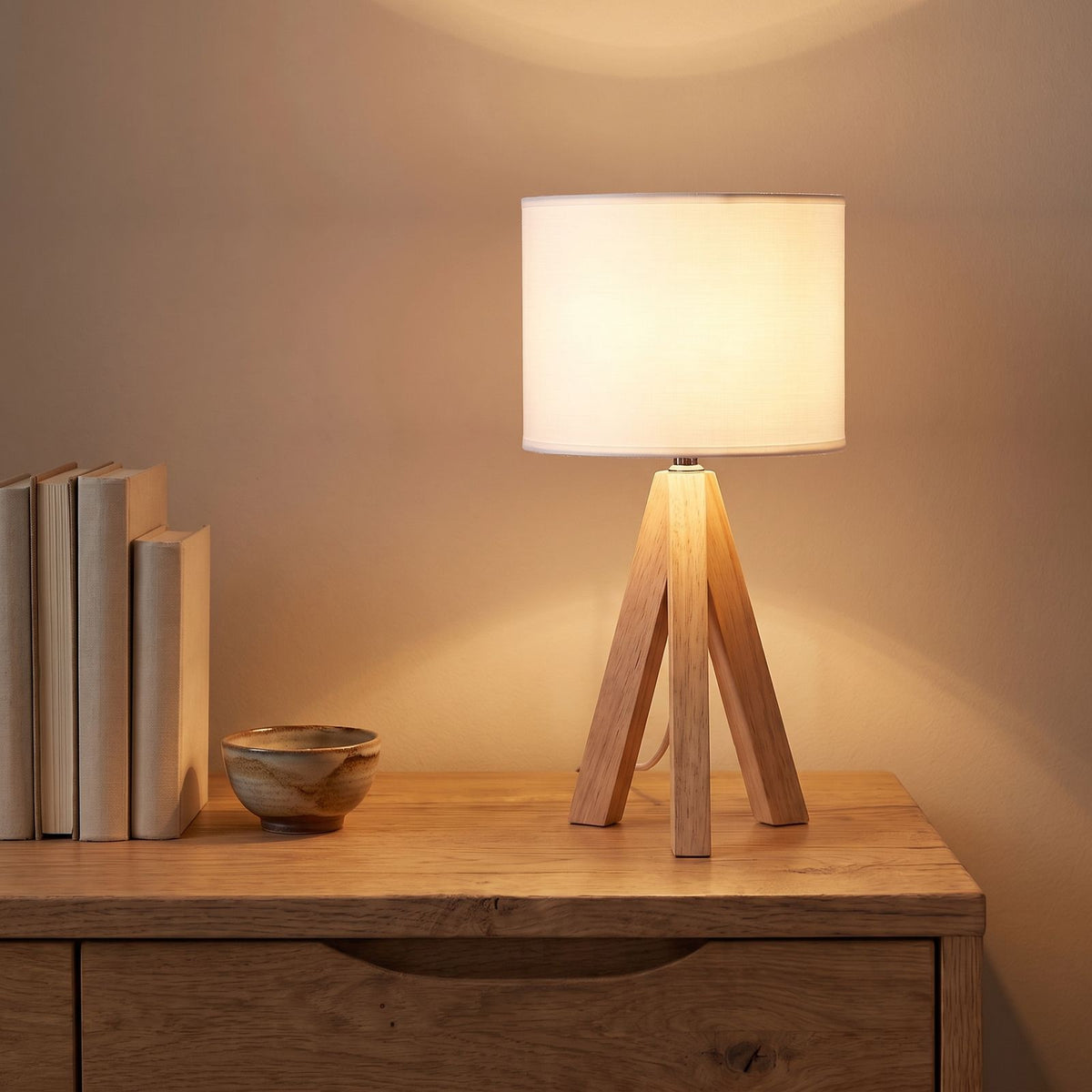 Wood tripod drum shade table lamp on an oak sideboard