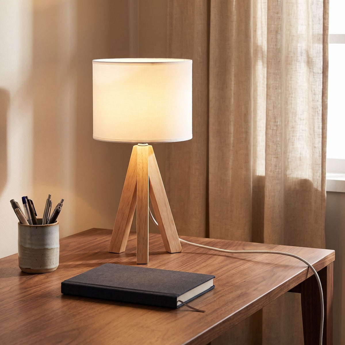 Wood tripod drum shade table lamp on a home office desk