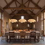 Three Woven Rattan Petal Flower Pendant Lights, Ø50 cm, in a row above a long dining table in a converted barn