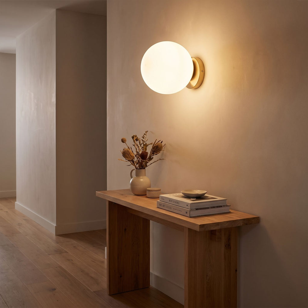 Wrought Iron Frame Glass Shade Wall Light in a hallway above a timber console