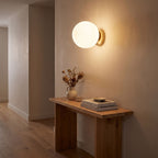 Wrought Iron Frame Glass Shade Wall Light in a hallway above a timber console