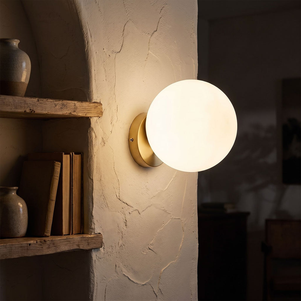 Wrought Iron Frame Glass Shade Wall Light glowing on a plaster wall at night