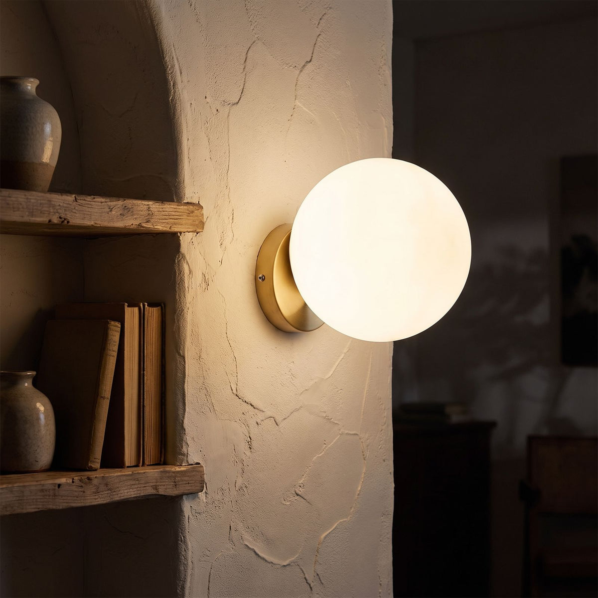 Wrought Iron Frame Glass Shade Wall Light glowing on a plaster wall at night